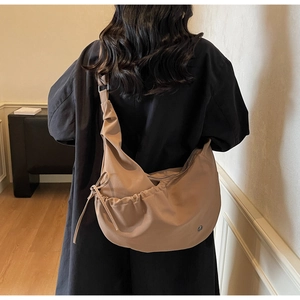 Detail of khaki oversized crossbody bag with drawstring design and soft fabric texture