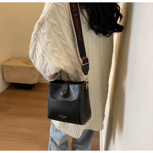 Détail du sac seau vintage noir avec bandoulière contrastée sur modèle
