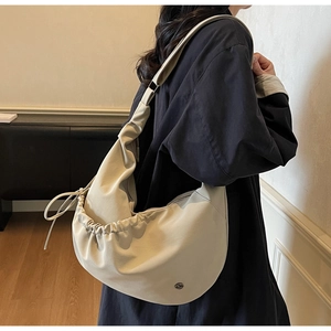 Detail view of cream oversized drawstring hobo bag showing soft draped fabric texture