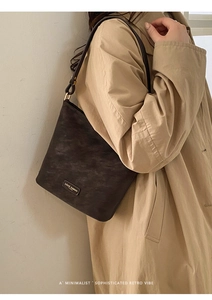 Nahaufnahme der dunkelbraunen Retro-Schultertasche mit strukturierter Oberfläche und Metall-Logo