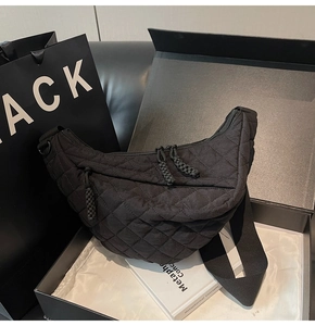 Détail du sac croissant matelassé noir avec tirettes de fermeture dans sa boîte