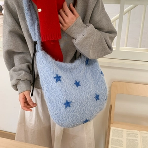 Close-up of light blue plush hobo bag featuring dark blue embroidered stars and drawstring
