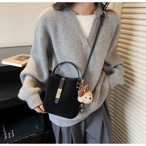 Détail du sac seau en daim noir avec fermoir doré et accessoire pendentif d'ours mignon