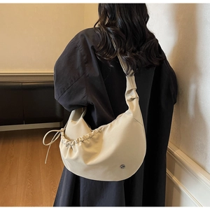 Detail view of beige crescent hobo bag featuring drawstring pleats and side texture