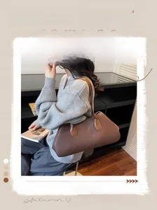 Detail of a brown leather tote bag with a minimalist rectangular profile and logo