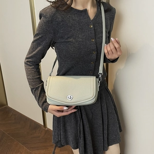 Detalle de bolso bandolera de cuero gris claro con grano y cierre giratorio plateado