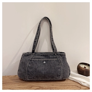 Close-up of a washed denim tote bag with front pocket and decorative metal button detail