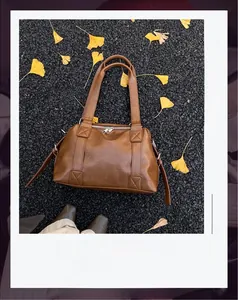 Detailed top view of a dark brown vintage faux leather tote bag on autumn ginkgo leaves