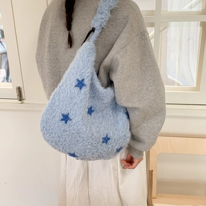 Detail of soft light blue plush shoulder bag with dark blue star patterns and fluffy texture