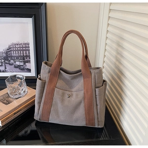 Detail of canvas tote bag with front snap pocket and woven handles for commute