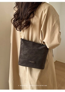 Detail der Vintage-Schultertasche mit goldener Metallplakette und feiner Hardware