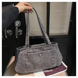Detail of washed denim tote bag featuring silver studs and white contrast stitching