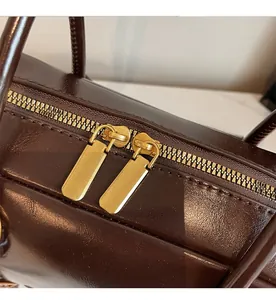 Close-up of smooth dual metal zippers on vintage dark brown leather boston bag