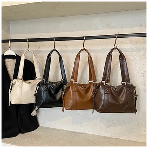 Detail view of large leather tote bags in four colors showing side cross-stitch craft