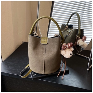 Detail der olivgrünen matten Beuteltasche mit rundem Griff und Plüschbär-Anhänger-Zubehör