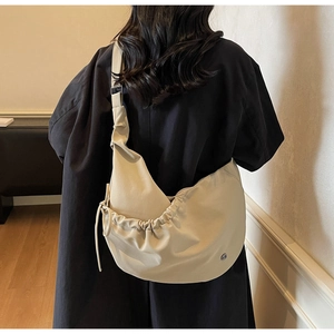 Detail of beige hobo bag showing adjustable strap and drawstring pleats on hobo fabric