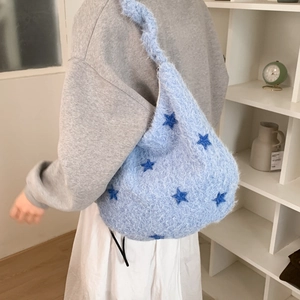 Detail of light blue plush tote bag with navy star patterns worn on shoulder