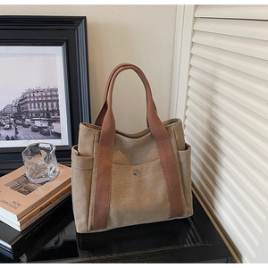Close-up of khaki canvas tote bag showing front pocket with silver snap button and side pockets