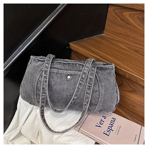 Detail of frayed edges and silver rivets on dark gray denim shoulder tote bag