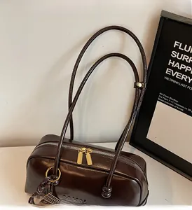 Detail of dark brown leather bowling bag with gold zippers and brand embossing