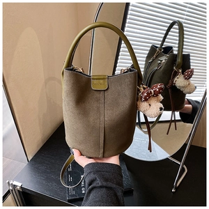 Detailansicht der dunkelgrünen Veloursleder-Beuteltasche mit Ledergriff und Teddybär-Anhänger