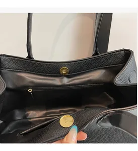Close-up of litchi grain texture, golden magnetic buckles and zipped pocket inside tote bag