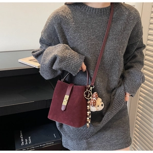 Detail of burgundy frosted bucket bag featuring golden metal lock and cute bear charm