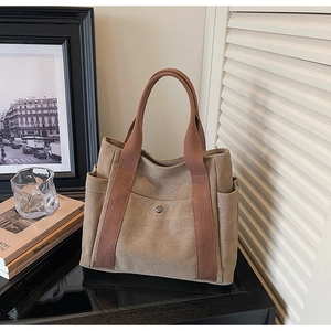 Detail of coffee brown canvas tote bag with woven handles and functional side pockets