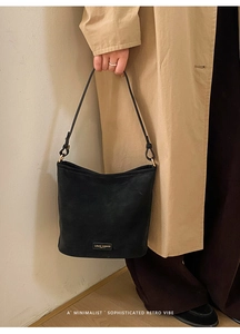 Nahaufnahme der schwarzen Beuteltasche mit Logo auf strukturiertem Wildleder-Material