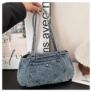Detail shot of blue denim shoulder bag featuring white stitching and silver snap button