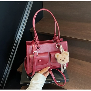 Close-up of wine red crossbody bag with functional front pockets and plush bear charm