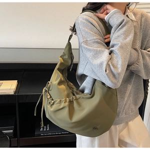 Detail of olive green crescent shoulder bag featuring side drawstring pleats and brand logo