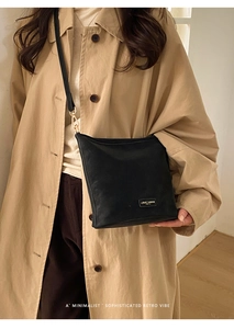 Detailaufnahme der schwarzen minimalistischen Umhängetasche mit Markenlogo-Plakette
