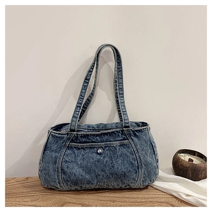 Detailed view of blue denim shoulder bag with white contrast stitching and metal rivets