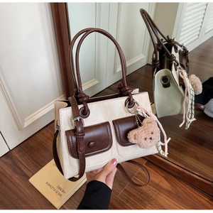 Detail view of contrast stitching handbag with plush bear charm and ribbon decor