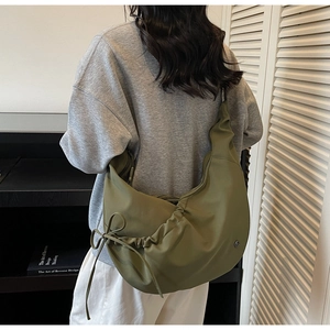 Side view of an olive green oversized crescent dumpling bag with drawstring bow detail