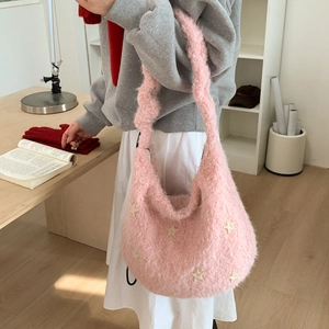 Detail of pink plush shoulder bag featuring cream star embroidery and soft texture