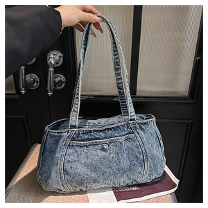 Close-up of blue washed denim shoulder bag with metal button and fabric texture