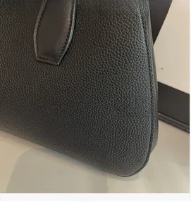 Macro shot of black lychee-textured leather tote bag with premium stitching detail
