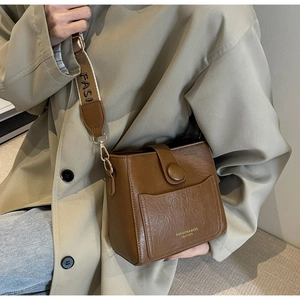 Gros plan du sac seau en cuir PU marron avec bandoulière tissée mode et boucle métallique