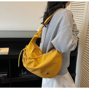 Detailed close-up of a bright yellow half-moon nylon bag with drawstring ruching