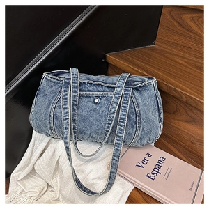 Detail of vintage blue denim shoulder bag featuring washed texture and front magnetic pocket