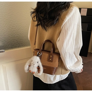 Dettaglio borsa a secchiello marrone patchwork con ciondolo a coniglio in peluche grigio