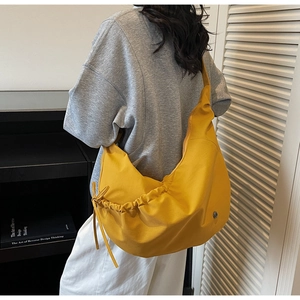 Side view of yellow hobo bag with drawstring detail and round metal logo on model