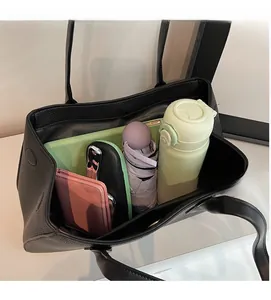Macro shot of spacious interior and magnetic closure on black litchi tote bag