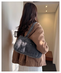 Detail of grey washed denim shoulder bag showing retro fabric texture and metal trim
