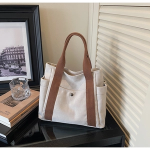Close-up of canvas tote bag showing metal buckle detail and side pocket functionality