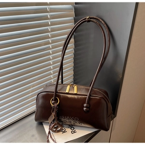 Detail of dark brown glossy leather shoulder bag with gold dual zippers and long handles