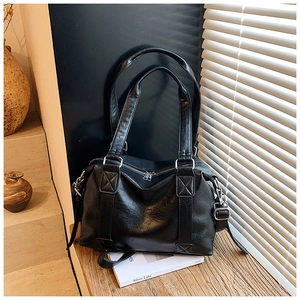 Close-up of black retro Boston bag with silver hardware on a wooden table with soft lighting