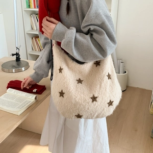 Close-up of plush off-white shoulder bag with brown star embroidery on a model